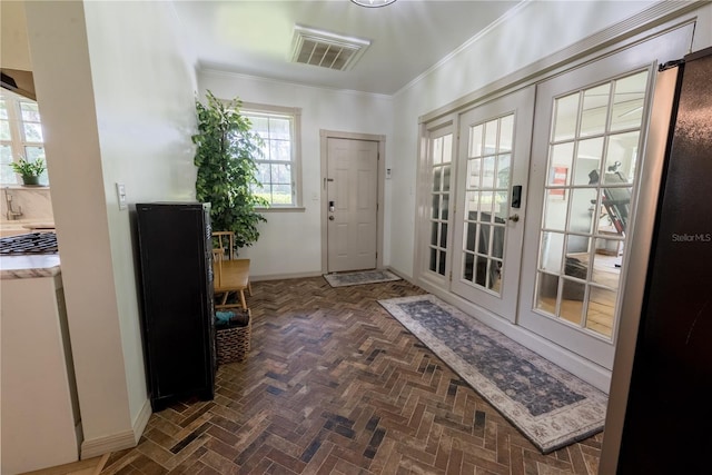 entryway with ornamental molding and french doors