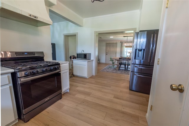 kitchen with white cabinets, crown molding, range hood, light hardwood / wood-style floors, and appliances with stainless steel finishes