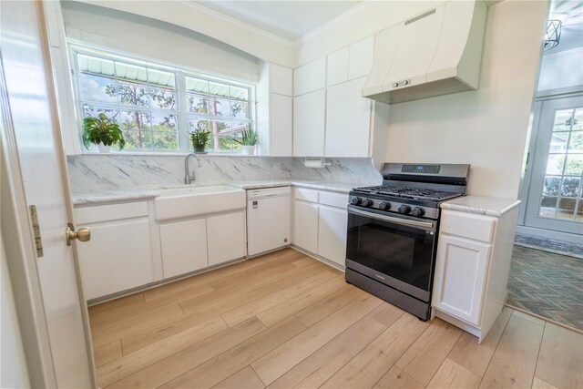 kitchen with gas range, white cabinets, premium range hood, and white dishwasher