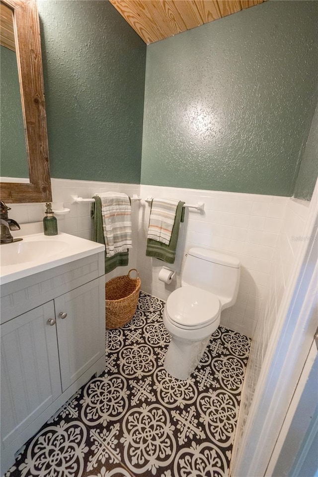 bathroom with tile patterned flooring, vanity, toilet, and tile walls