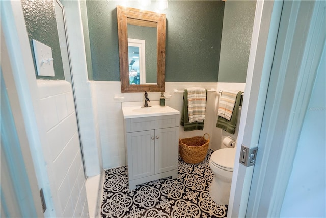 bathroom with vanity, tile patterned flooring, toilet, and tile walls