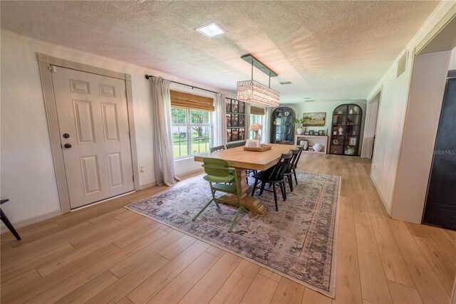 dining area with a textured ceiling and light hardwood / wood-style floors