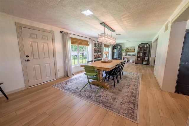 dining space with a textured ceiling and light hardwood / wood-style flooring