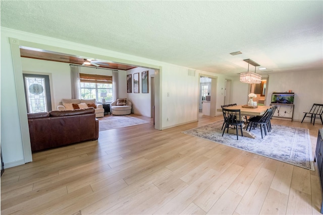 dining space with ceiling fan with notable chandelier, light hardwood / wood-style flooring, and a textured ceiling