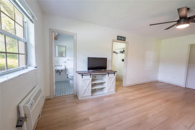 living room featuring a wall unit AC, light hardwood / wood-style floors, and ceiling fan