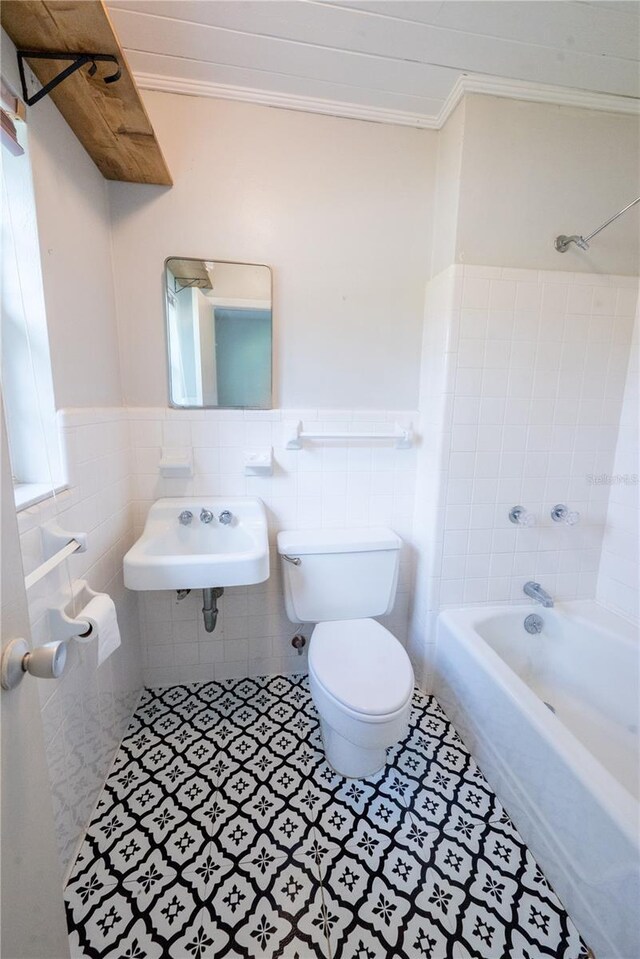 full bathroom featuring tile patterned flooring, crown molding, shower / tub combination, toilet, and tile walls