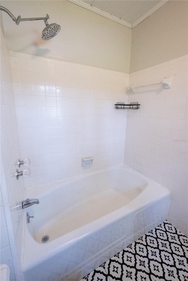 bathroom featuring tile patterned flooring, tiled shower / bath combo, and tile walls