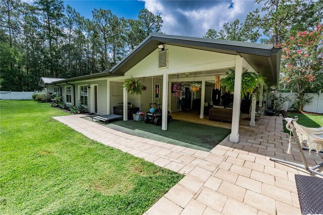 back of property featuring ceiling fan, a patio, and a lawn