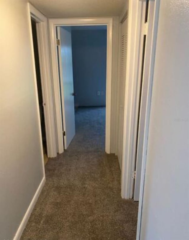 hall with dark colored carpet