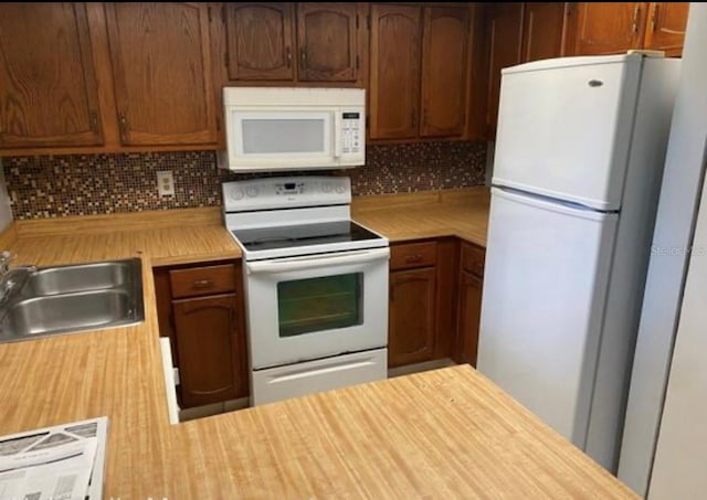 kitchen with sink, backsplash, and white appliances