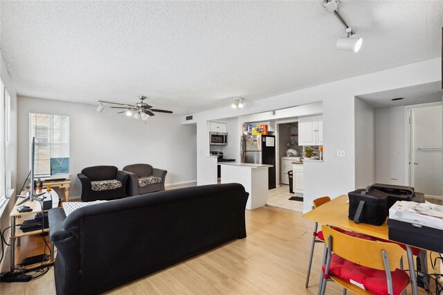 living room featuring rail lighting, light hardwood / wood-style floors, ceiling fan, and a textured ceiling