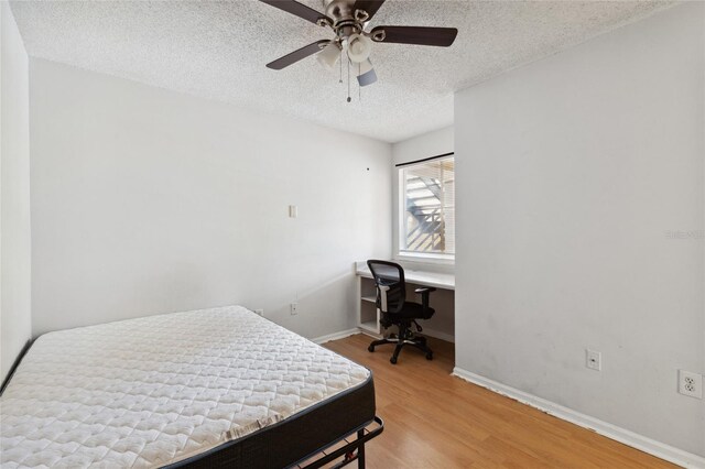 bedroom with ceiling fan, hardwood / wood-style floors, and a textured ceiling