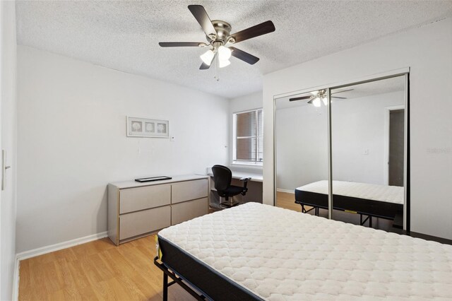 bedroom with light wood-type flooring, a textured ceiling, ceiling fan, and a closet