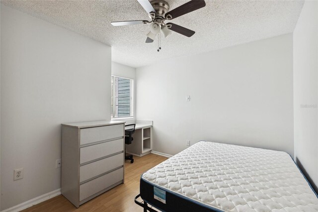 bedroom with ceiling fan, a textured ceiling, and light hardwood / wood-style floors