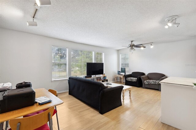 living room featuring light wood-type flooring, a textured ceiling, ceiling fan, and track lighting