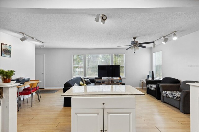 kitchen featuring rail lighting, light hardwood / wood-style floors, ceiling fan, and white cabinets