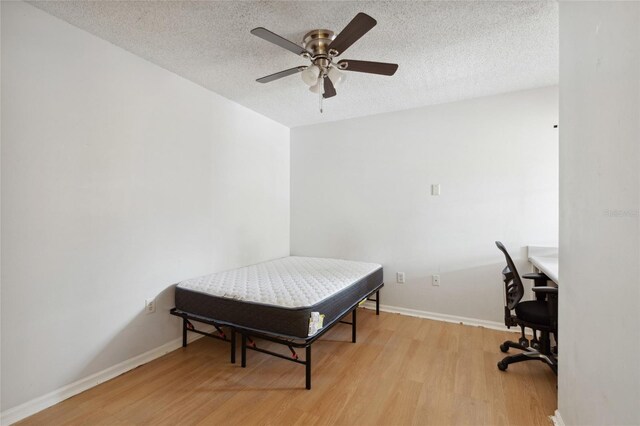 bedroom featuring light hardwood / wood-style flooring, a textured ceiling, and ceiling fan