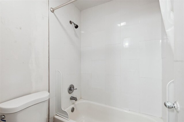 bathroom with tiled shower / bath combo and toilet