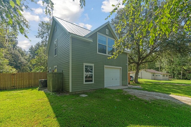 view of front of house with a garage, a front lawn, and central AC unit