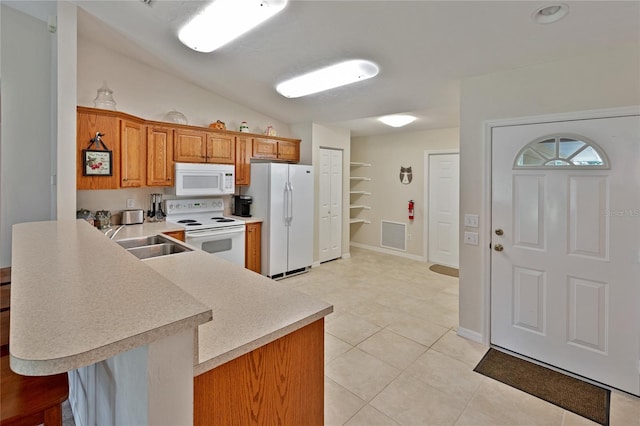 kitchen with white appliances, light tile patterned floors, kitchen peninsula, a kitchen breakfast bar, and sink