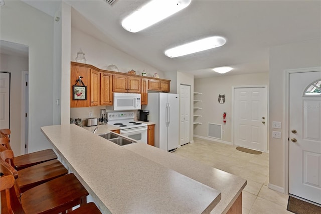 kitchen featuring white appliances, sink, kitchen peninsula, light tile patterned floors, and lofted ceiling