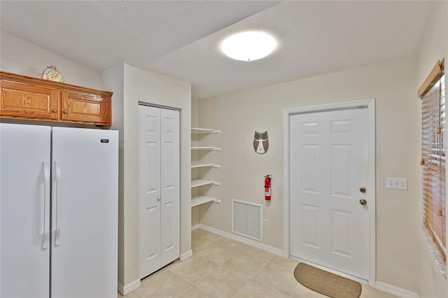 kitchen with white fridge and light tile patterned floors