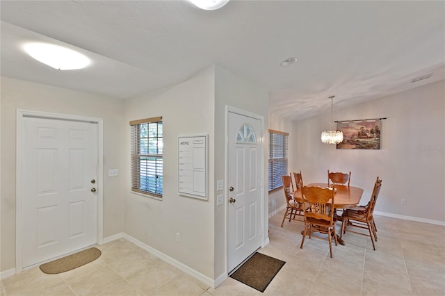 tiled foyer featuring an inviting chandelier and lofted ceiling