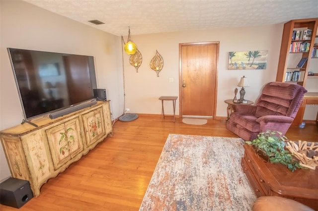 living room with a textured ceiling and light wood-type flooring