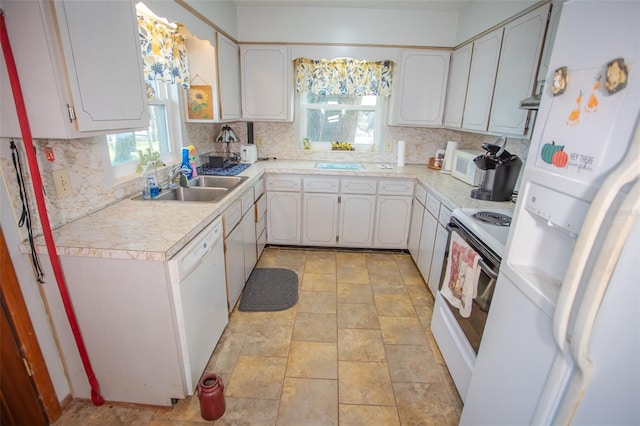 kitchen featuring sink, white appliances, backsplash, a healthy amount of sunlight, and white cabinets