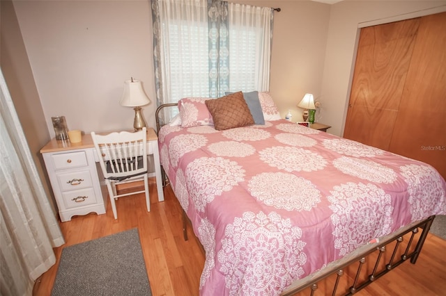 bedroom with light hardwood / wood-style floors and a closet