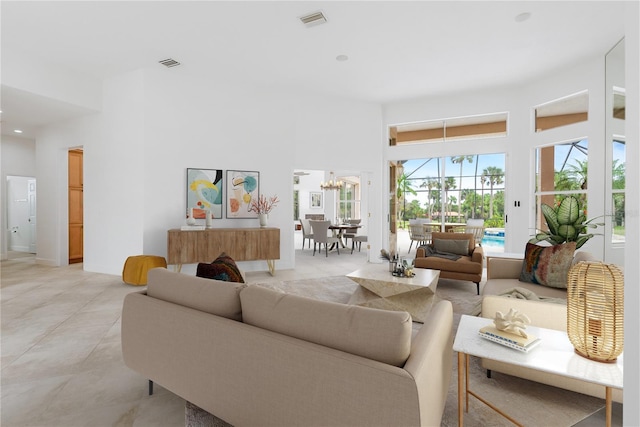 living area with light tile patterned floors, visible vents, an inviting chandelier, and a towering ceiling