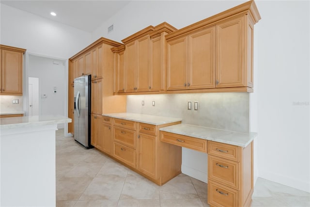 kitchen featuring built in desk, light tile patterned flooring, and stainless steel refrigerator with ice dispenser