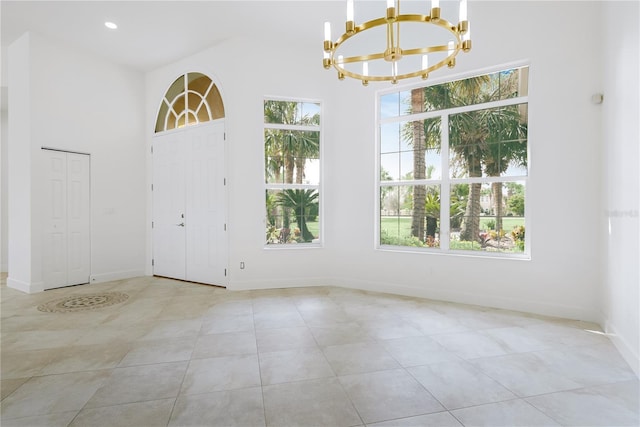 foyer entrance featuring light tile patterned floors, baseboards, an inviting chandelier, a high ceiling, and recessed lighting