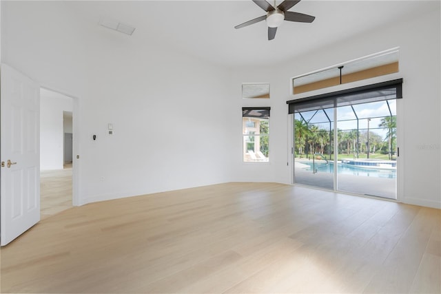 spare room featuring a sunroom, light wood finished floors, and ceiling fan