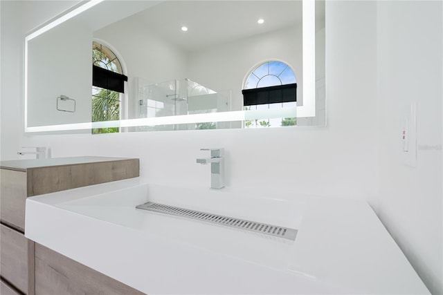 bathroom with plenty of natural light, recessed lighting, a walk in shower, and a sink