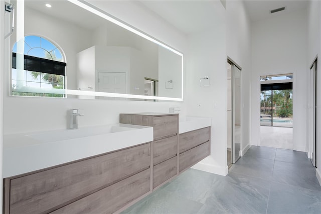 full bathroom featuring visible vents, recessed lighting, baseboards, a towering ceiling, and vanity