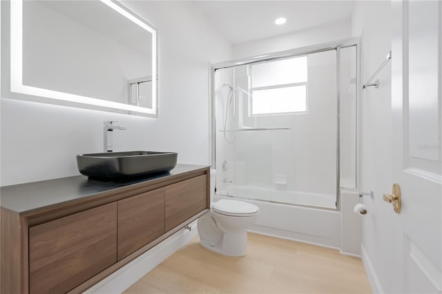 full bathroom featuring enclosed tub / shower combo, vanity, toilet, and wood-type flooring