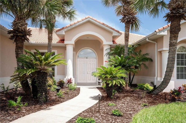 property entrance with stucco siding and a tiled roof