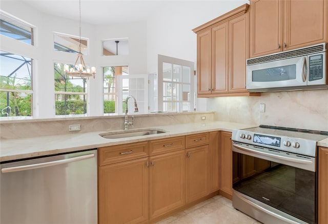 kitchen featuring light stone counters, light tile patterned flooring, a sink, stainless steel appliances, and a notable chandelier