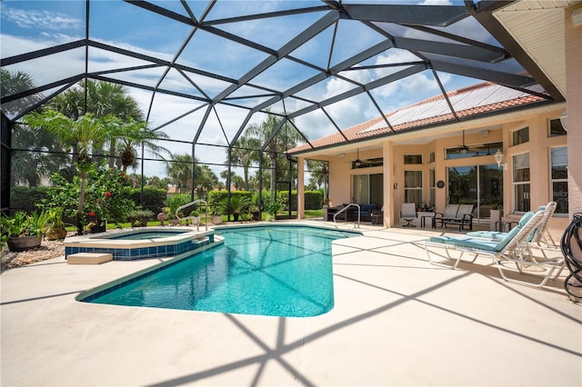 view of swimming pool with glass enclosure, a pool with connected hot tub, ceiling fan, and a patio area