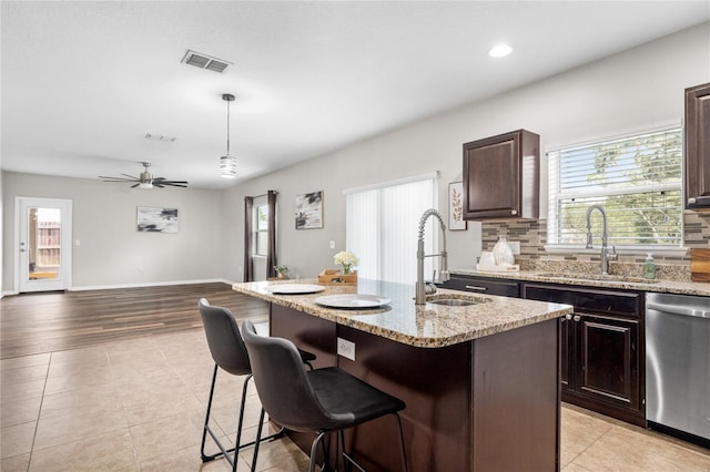 kitchen with light hardwood / wood-style flooring, pendant lighting, stainless steel dishwasher, an island with sink, and ceiling fan