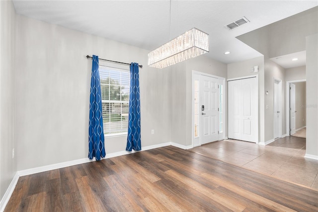 unfurnished room featuring an inviting chandelier and hardwood / wood-style floors