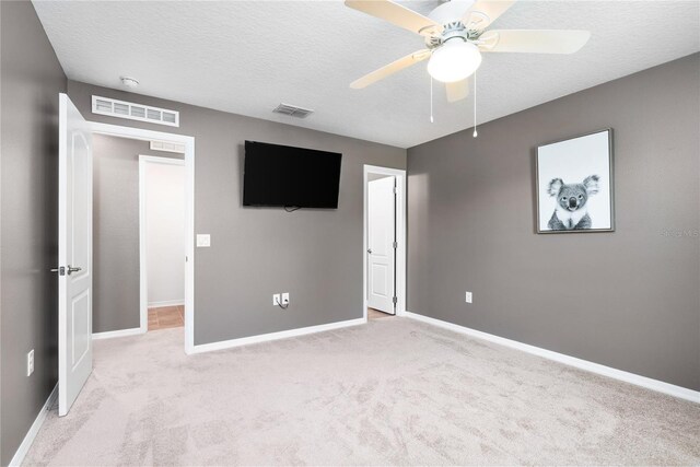 unfurnished bedroom with a textured ceiling, light colored carpet, and ceiling fan