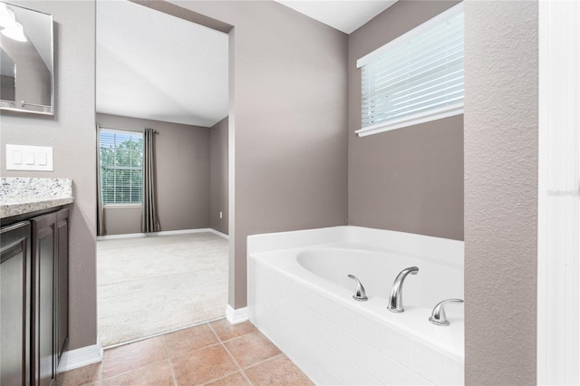 bathroom featuring tiled bath, vanity, and tile patterned flooring