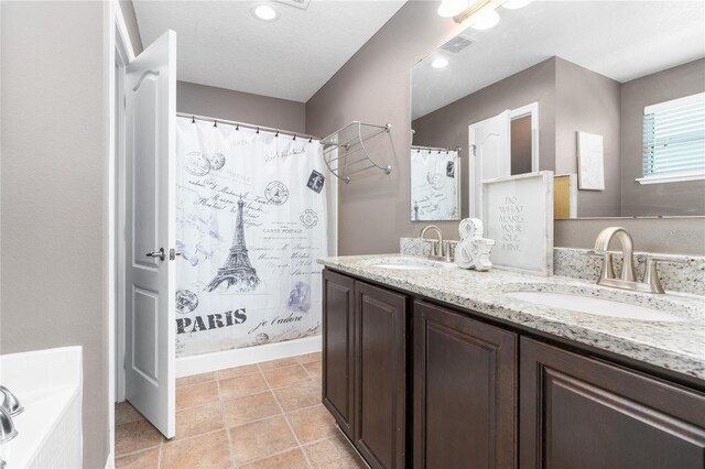 bathroom with dual bowl vanity, a bath, and tile patterned flooring