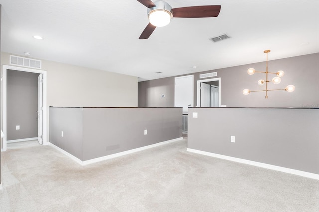 carpeted spare room with ceiling fan with notable chandelier