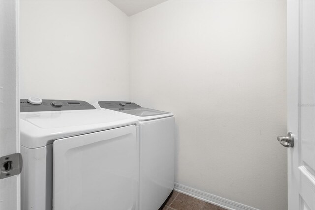 laundry area with dark tile patterned flooring and washer and clothes dryer