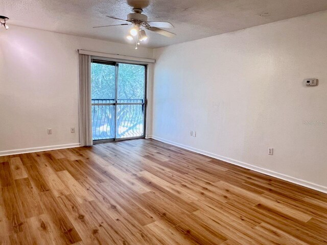 empty room featuring a textured ceiling, ceiling fan, wood finished floors, and baseboards