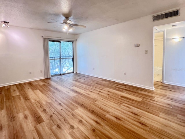 unfurnished room with light wood-type flooring, visible vents, a textured ceiling, and baseboards