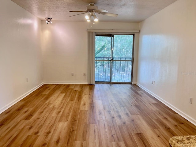 empty room featuring a textured ceiling, ceiling fan, wood finished floors, and baseboards